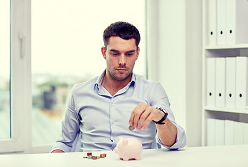 Image showing businessman with piggy bank and coins at office