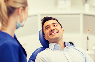 Image showing female dentist with happy male patient at clinic