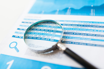 Image showing close up of financial report and magnifying glass