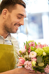 Image showing smiling florist man making bunch at flower shop