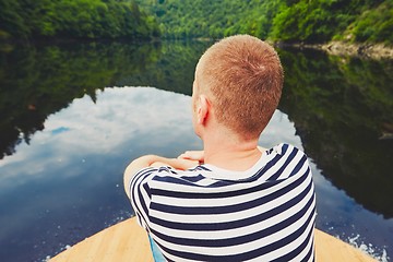 Image showing Vacation trip on the river. Handsome man is sitting on the prow of the boat