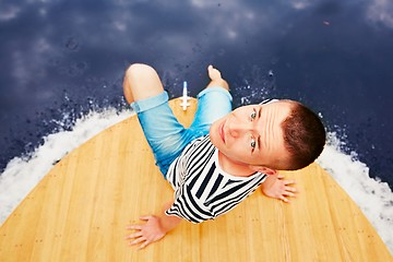 Image showing Vacation trip on the river. Handsome man is sitting on the prow of the boat