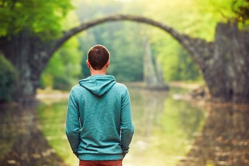 Image showing Pensive man is looking at the old bridge