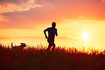 Image showing Athletic runner with dog at the sunset