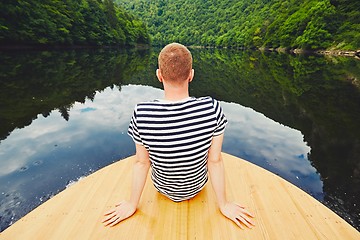 Image showing Vacation trip on the river. Handsome man is sitting on the prow of the boat