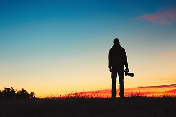 Image showing Silhouette of young photographer is enjoying sun. Photographer at the sunrise