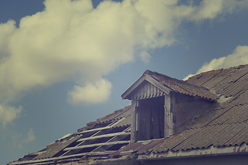 Image showing Old tile roof with holes and sky with clouds