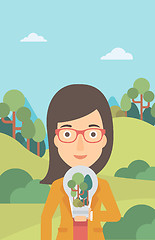 Image showing Woman with lightbulb and trees inside.