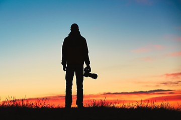 Image showing Silhouette of young photographer is enjoying sun. Photographer at the sunrise