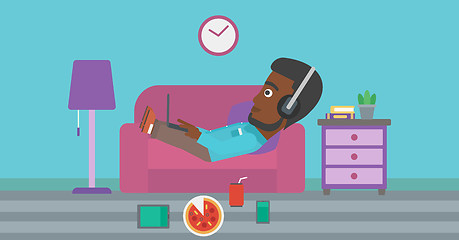 Image showing Man lying on sofa with many gadgets.