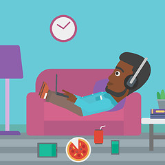 Image showing Man lying on sofa with many gadgets.