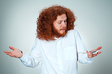 Image showing Portrait of puzzled man talking on the phone  a gray background