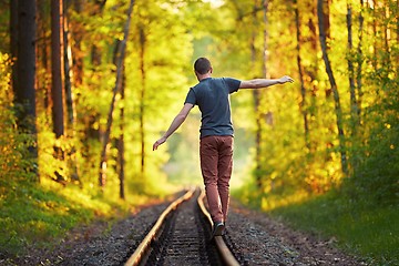 Image showing Young man walking on the railway