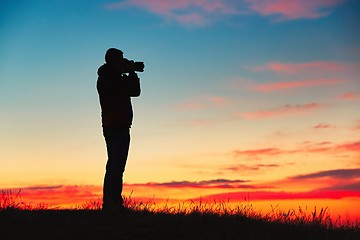 Image showing Silhouette of young photographer is enjoying sun. Photographer at the sunrise