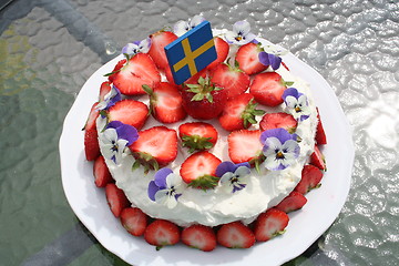 Image showing Gateau with strawberries, Swedish flag and pansies