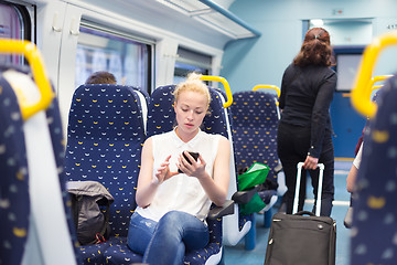 Image showing Woman using mobile phone while travelling by train.