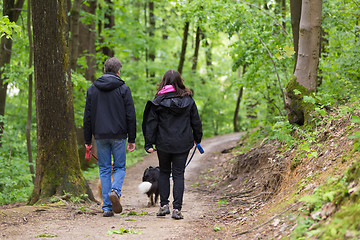 Image showing Couple walking their two dogs in forest