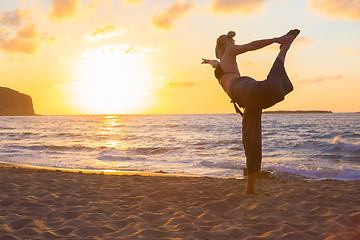 Image showing Woman practicing yoga on sea beach at sunset.