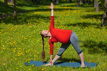 Image showing Pregnant woman doing asana Utthita trikonasana outdoors