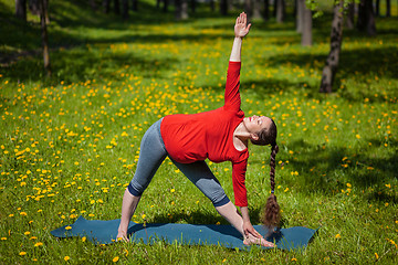 Image showing Pregnant woman doing asana Utthita trikonasana outdoors