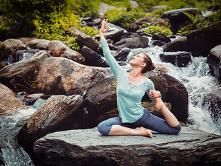 Image showing Sorty fit woman doing yoga asana outdoors at tropical waterfall