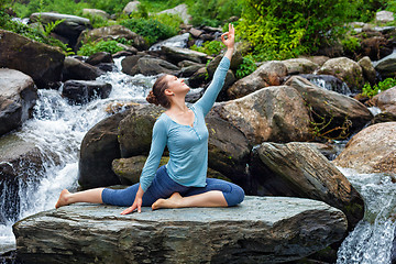 Image showing Sorty fit woman doing yoga asana outdoors at tropical waterfall