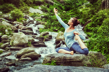 Image showing Sorty fit woman doing yoga asana outdoors at tropical waterfall