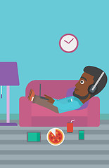 Image showing Man lying on sofa with many gadgets.