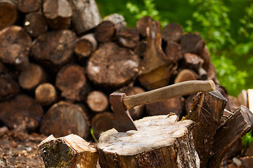 Image showing Old ax on log and firewood in the background