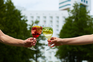 Image showing Hand holding glasses cocktail clinking together at outdoor.