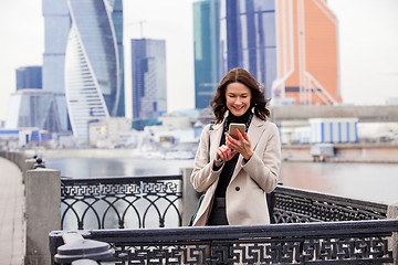 Image showing smiling beautiful middle-aged woman with a smartphone