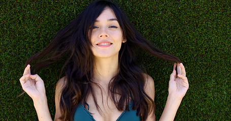 Image showing Pretty woman with long brown hair lays in grass