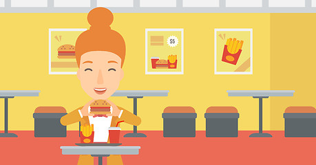 Image showing Woman eating hamburger. 