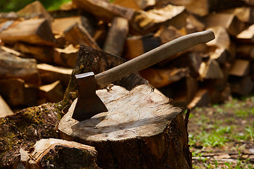 Image showing Old ax on log and firewood in the background