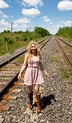 Image showing Young woman walking on railroad track's.