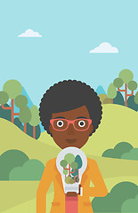 Image showing Woman with lightbulb and trees inside.