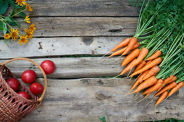 Image showing Fresh carrots bunch and tomatoes on rustic wooden background