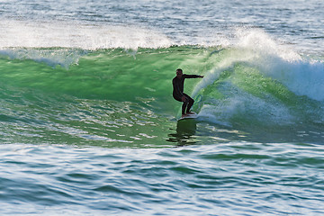 Image showing Long boarder surfing the waves at sunset