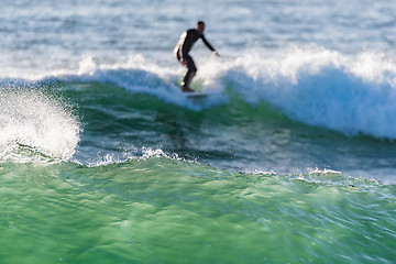 Image showing Long boarder surfing the waves at sunset