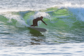 Image showing Long boarder surfing the waves at sunset