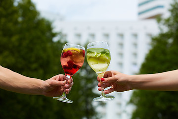 Image showing Hand holding glasses cocktail clinking together at outdoor.