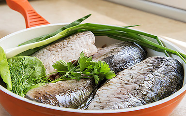 Image showing Fish and components for her preparation in a large skillet.