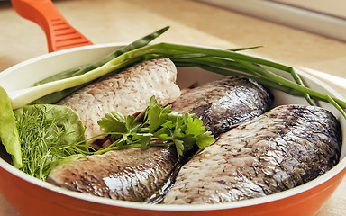 Image showing Fish and components for her preparation in a large skillet.