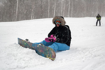 Image showing Woman with snowboard rests on snow