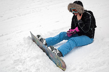 Image showing Woman with snowboard rests on snow