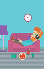 Image showing Man lying on sofa with many gadgets.