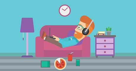 Image showing Man lying on sofa with many gadgets.