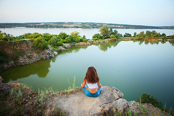 Image showing Young woman is practicing yoga near river