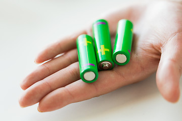 Image showing close up of hand holding green alkaline batteries