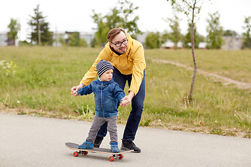 Image showing happy father and little son on skateboard